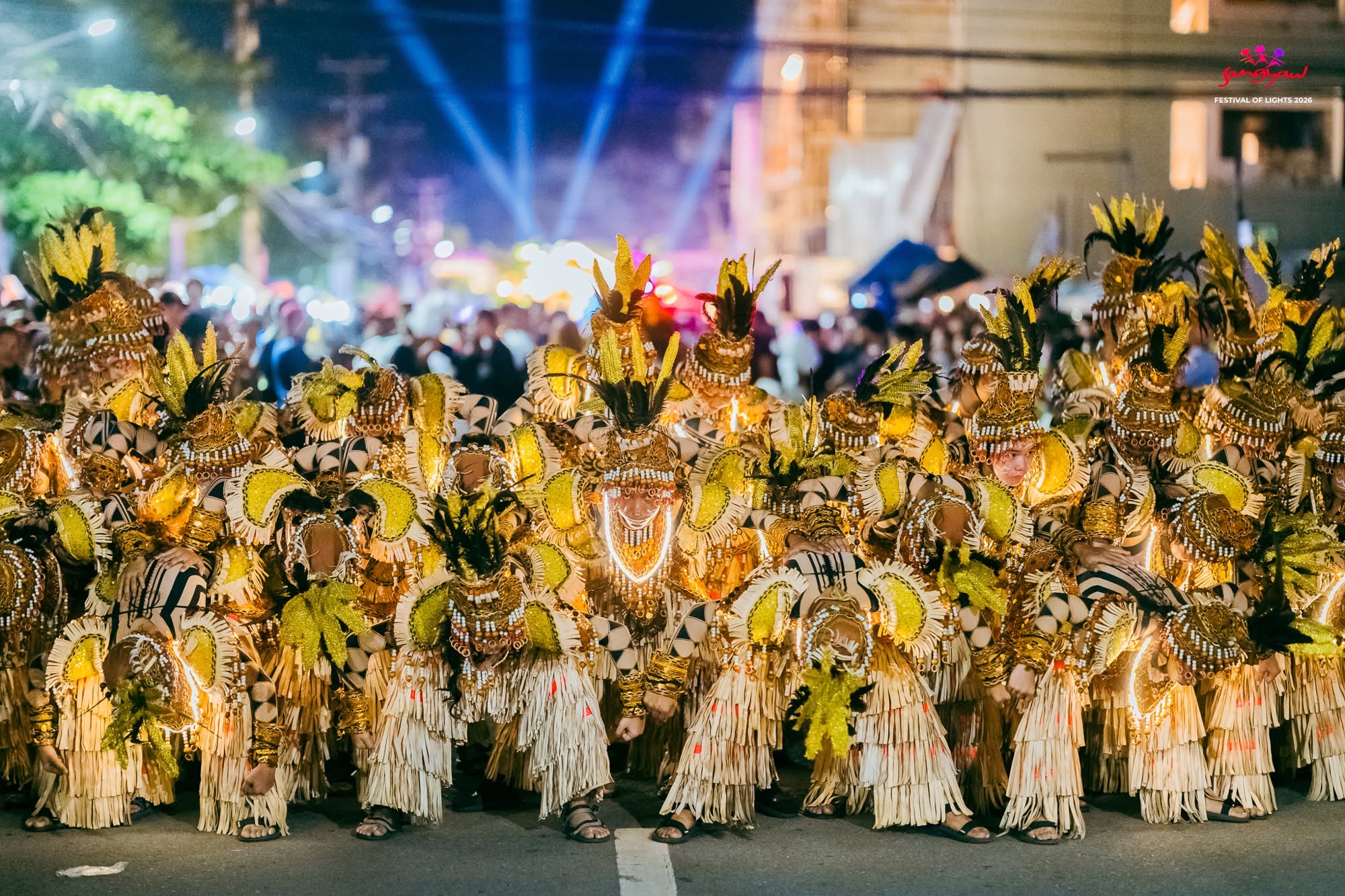 Sangyaw performers in gold and black costumes gathered beneath festival lights
